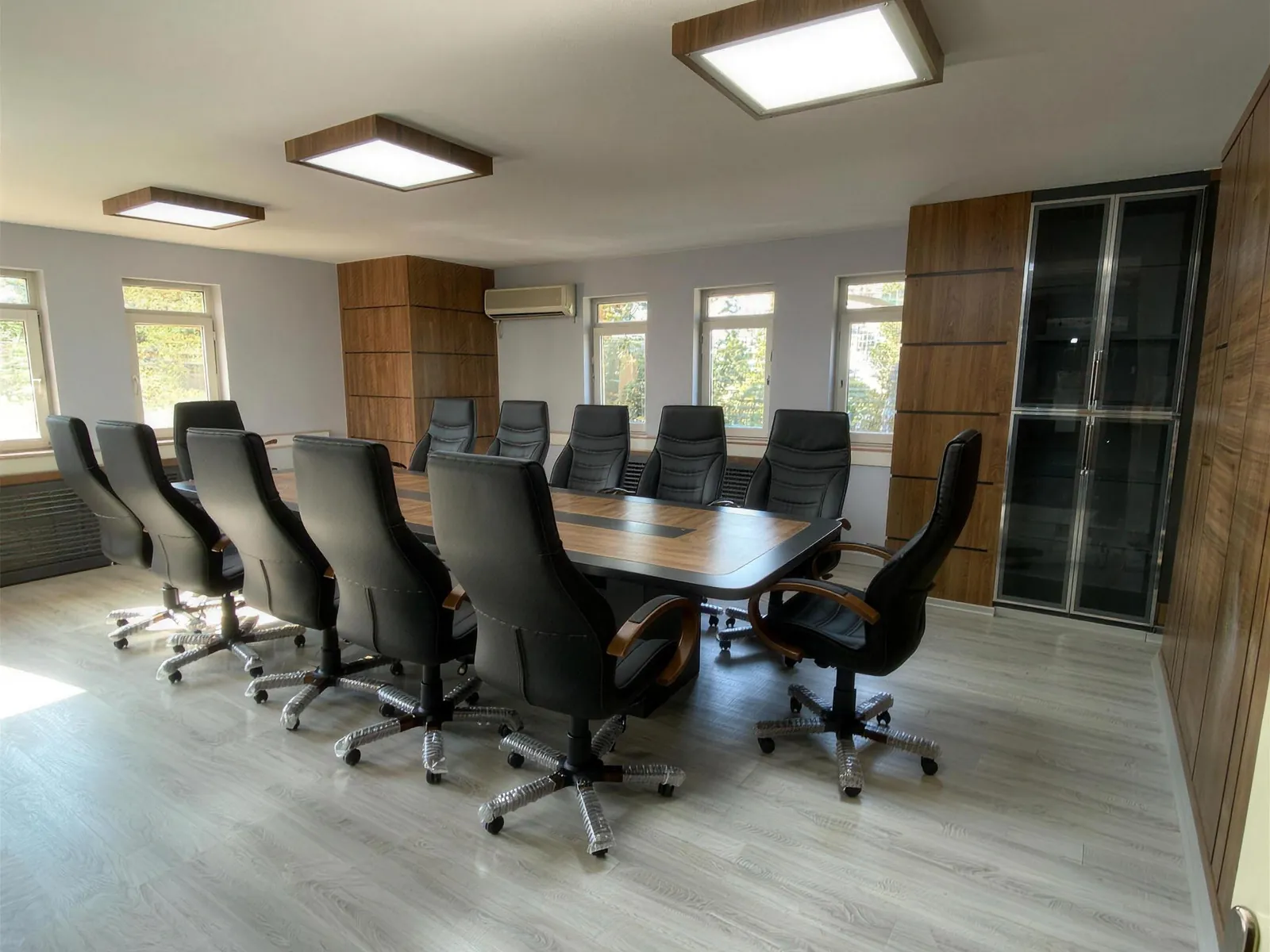 Boardroom with veneered wall cabinets and a conference table ringed by leather chairs
